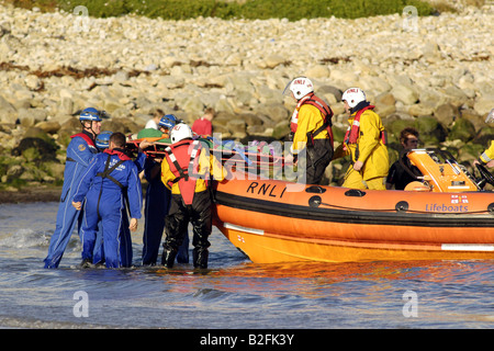 Küstenwache am Ufer Rettung Freiwilligen in seinem blauen Overalls heben einen Körper auf einem Rettungsboot warten Stockfoto