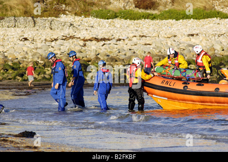Küstenwache am Ufer Rettung Freiwilligen in seinem blauen Overalls heben einen Körper auf einem Rettungsboot warten Stockfoto