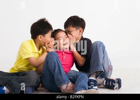 Zwei Jungs in ein Mädchen Ohren flüstern Stockfoto