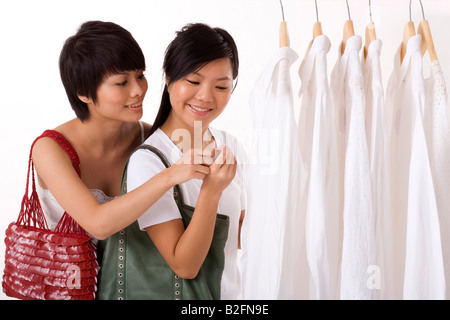 Zwei junge Frauen, Blick auf das Preisschild eines Kleides in einem Bekleidungsgeschäft Stockfoto