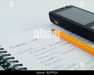 Home Business Budget mit Handy auf Ringbound gesäumten weißen Notizpapier Stockfoto