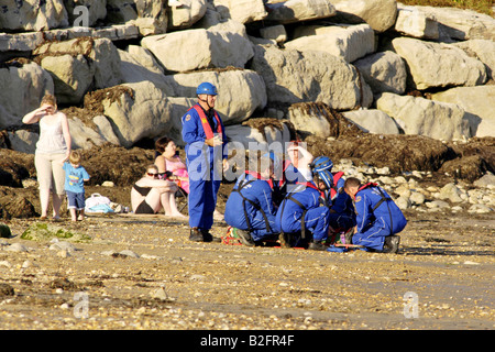 Küstenwache am Ufer Rettung Freiwilligen in blauen Overalls finden eine Stelle am Strand Stockfoto
