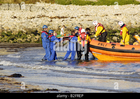 Küstenwache am Ufer Rettung Freiwilligen in seinem blauen Overalls heben einen Körper auf einem Rettungsboot warten Stockfoto
