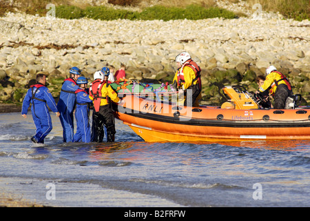 Küstenwache am Ufer Rettung Freiwilligen in seinem blauen Overalls heben einen Körper auf einem Rettungsboot warten Stockfoto