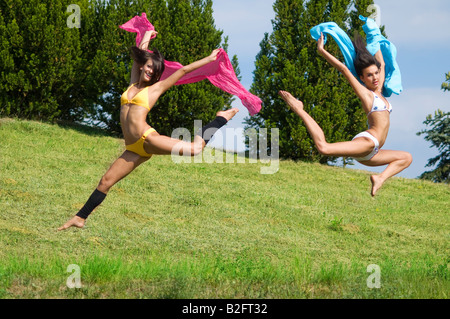 zwei tolle Mädchen springen Tougheter in einem Feld mit rosa und blauen scarfe Stockfoto