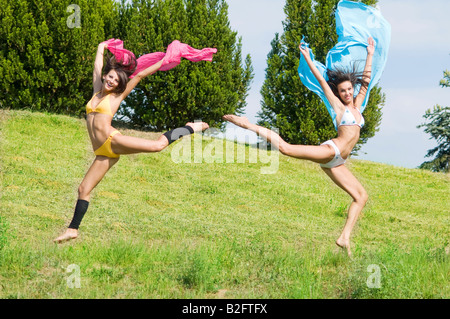 zwei tolle Mädchen springen Tougheter in einem Feld mit rosa und blauen scarfe Stockfoto