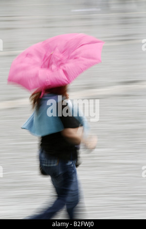 Person mit Regenschirm bei starkem Regen in der Stadt Stockfoto