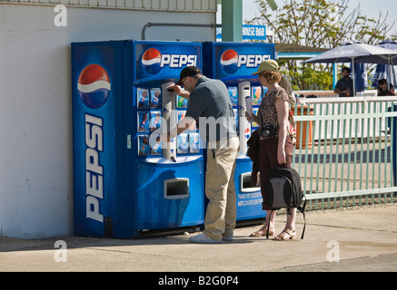 Erwachsener Mann und Frau Pepsi aus einem Automaten zu kaufen, an einem heißen sonnigen Tag Stockfoto