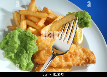 Fisch, Chips und Erbsenpüree auf einem weißen Teller mit einer Gabel geschlagen Stockfoto