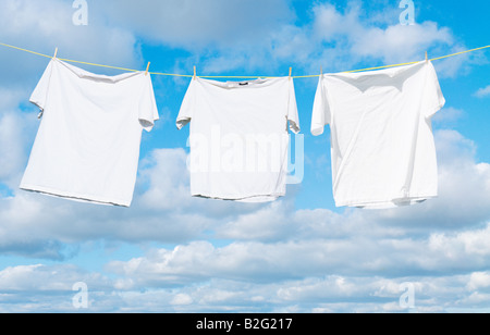 Weiße Hemden hängen auf einer Wäscheleine vor einem Himmel voller geschwollene weiße Wolken Stockfoto