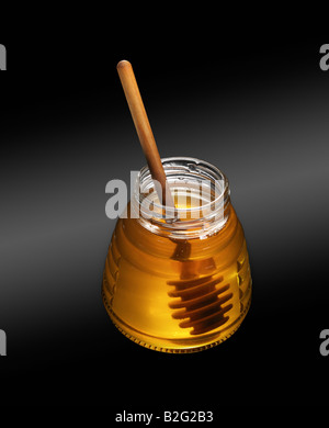 Glasglas Honig auf schwarzem Hintergrund mit hölzernen Honig dipper Stockfoto