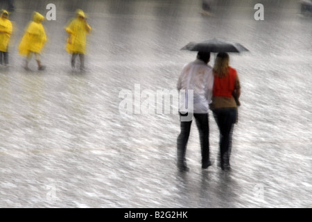 junges Paar teilen einen Regenschirm bei starkem Regen Stockfoto