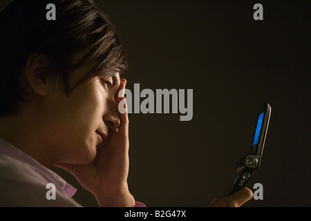 Nahaufnahme eines jungen Mannes hält ein Handy und suchen traurig Stockfoto