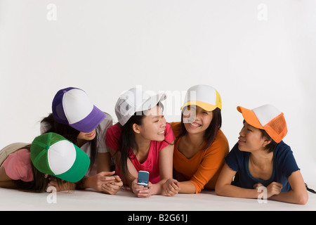Fünf junge Frauen auf dem Boden liegend und lächelnd zusammen Stockfoto