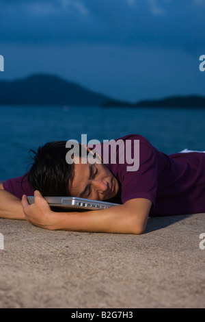 Seitenansicht der Mitte erwachsener Mann mit einem Laptop am Strand liegen Stockfoto