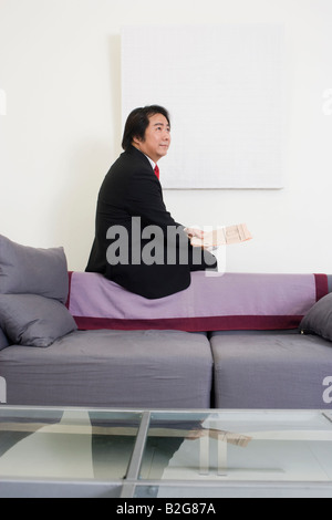 Seitenansicht eines Geschäftsmannes auf einer Couch sitzen und denken Stockfoto