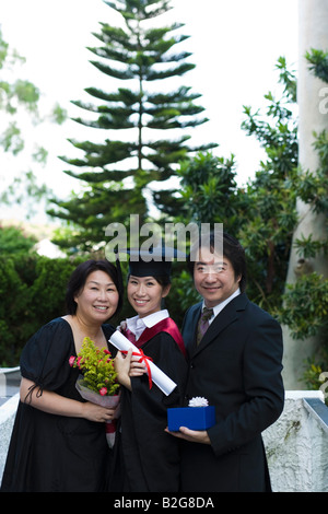 Porträt der weiblichen Absolventen Diplom und stehen mit ihren Eltern Stockfoto