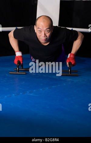 Reifer Mann mit Push-up-Bars in einem Boxring Ausübung Stockfoto