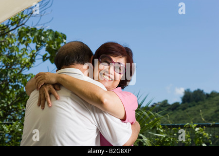 Reife Frau umarmt einen älteren Mann lächelnd Stockfoto