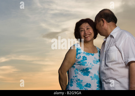 Niedrigen Winkel Ansicht eines älteren Mannes in Reife Frau Ohr flüstern Stockfoto