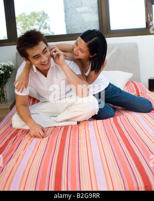 Junger Mann im Gespräch auf ein Mobiltelefon und eine Mitte Frau neben ihm zu sitzen Stockfoto