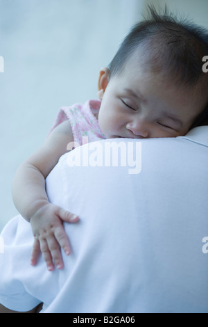 Nahaufnahme von einem Babymädchen schlafen auf ihres Vaters Schulter Stockfoto