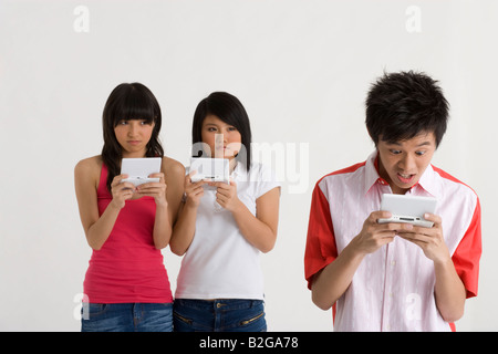 Nahaufnahme eines jungen Mannes mit einem PDA mit zwei jungen Frauen, die hinter ihm steht Stockfoto