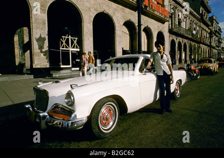 Mann stand neben seinem weißen amerikanischen Oldtimer, geparkt in einer Straße in Havanna, Kuba Stockfoto