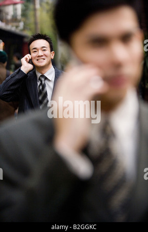 Zwei Geschäftsleute sprechen auf dem Handy, Shanghai, China Stockfoto