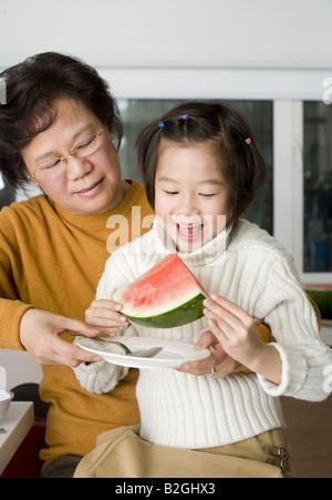 Nahaufnahme eines Mädchens mit ihrer Großmutter sitzen und Essen ein Stück Wassermelone Stockfoto