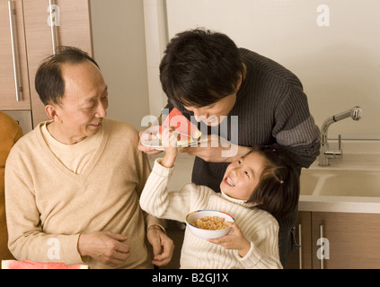 Nahaufnahme eines Mädchens Fütterung ihres Vaters und ein senior Mann sitzt neben Ihnen Stockfoto