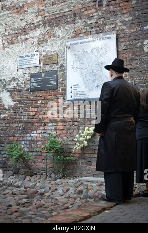 Ein chassidischen jüdischen Mann und seine Frau stehen vor einer der zwei verbliebenen Teile der Warschauer Ghetto Mauer. Stockfoto