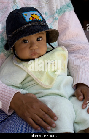 Ecuadorianische jungen Kind auf Mutters Schoß, trägt schwarze hat.facing. Otavalo 70394 Ecuador Otavalo Stockfoto