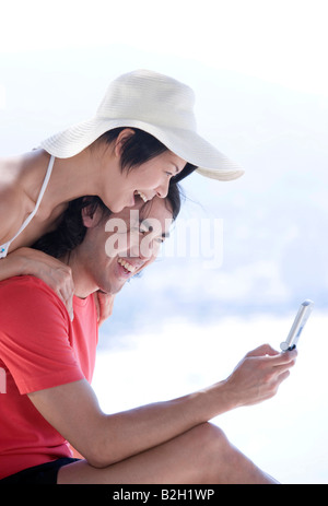 Seitenansicht eines Paares Blick auf ein Mobiltelefon und lachen Stockfoto