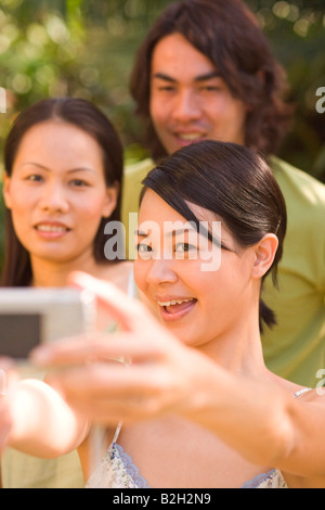 Nahaufnahme einer jungen Frau ein Foto von sich selbst mit einer digitalen Kamera und lächelnd Stockfoto