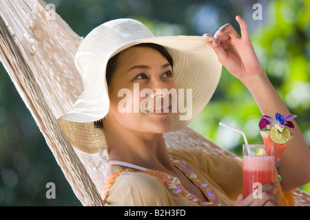 Nahaufnahme einer jungen Frau in einer Hängematte liegend und hält ein Glas Cocktail, Phuket, Thailand Stockfoto