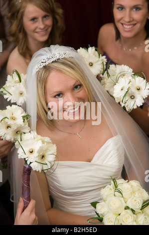 lächelnde junge blonde Braut umgeben ihre Brautjungfern holding Blumensträuße, Wales UK Stockfoto