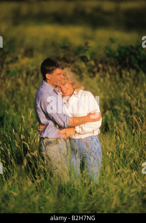 Junges Lächeln paar umarmt und in einem Feld stehen. Stockfoto