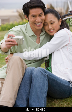 Mitte erwachsenen Mannes mit dem Fotografieren mit einer jungen Frau sitzt neben ihm, Huntington Beach, Kalifornien, USA Stockfoto