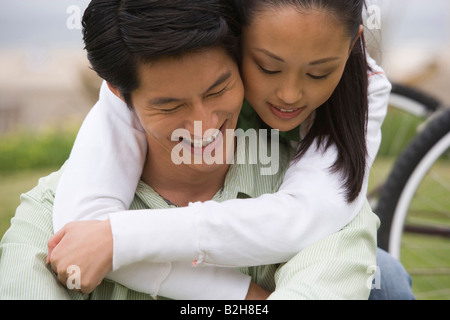Nahaufnahme einer jungen Frau einen Mitte erwachsenen Mann von hinten umarmt und lächelnd, Huntington Beach, Kalifornien, USA Stockfoto