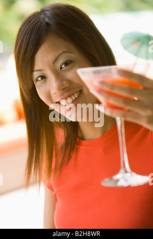 Porträt einer jungen Frau hält eine Glas Weine und lächelnd, Singapur Stockfoto