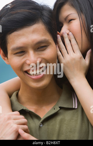 Nahaufnahme einer jungen Frau, die ein junger Mann Ohr flüstern Stockfoto