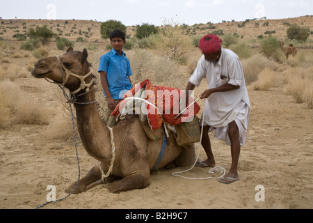 Eine Wüste GUIDE lädt seine Kamel Camelus Bactrianus in der THAR-Wüste in der Nähe von JAISALMER RAJASTHAN Indien Stockfoto