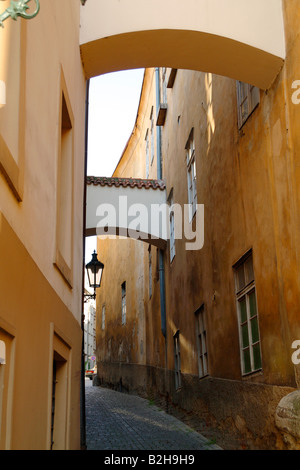 Eine schmale Kopfsteinpflaster Stein Straße in Prag mit rustikalen Gebäuden mit Bögen auf beiden Seiten der Straße verbunden Stockfoto