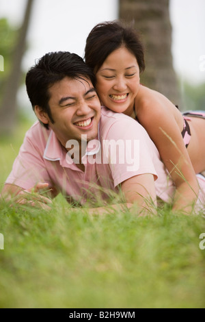 Junge Frau liegend auf einem jungen Mann lächelnd Stockfoto