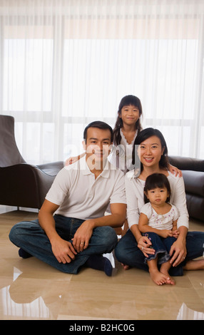 Porträt eines Mitte Erwachsenen Paares sitzen mit ihren beiden Töchtern auf dem Boden, Singapur Stockfoto