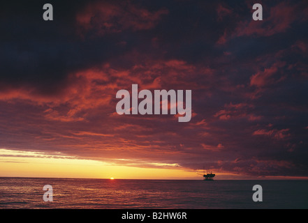 Sonnenuntergang mit Wolken über Meer mit off Shore Ölplattform in der Ferne. Stockfoto