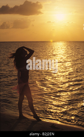 Silhouette einer Frau stehen am Strand bei Sonnenuntergang. Stockfoto