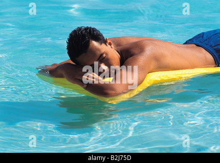 Malediven. Junger Mann in Badehose auf Luft Bett schwebend auf kristallklarem Wasser. Stockfoto