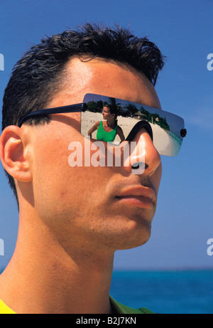 Malediven. Outdoor Portrait eines jungen Mann mit verspiegelten Sonnenbrillen mit reflektierte Bild der jungen Frau am tropischen Strand. Stockfoto